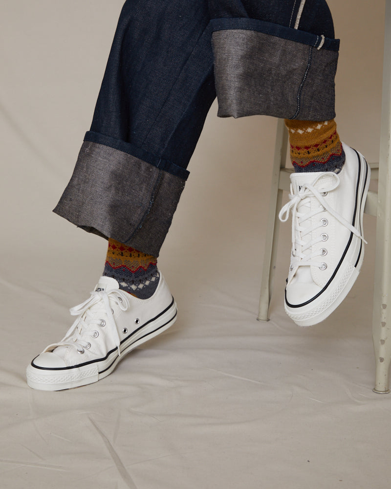 ANTIPAST COLLECTION IMAGE SHOWING MODEL FROM THE ANKLES DOWN WEARING JEANS, STATEMENT PRINTED SOCKS, AND WHITE SNEAKERS