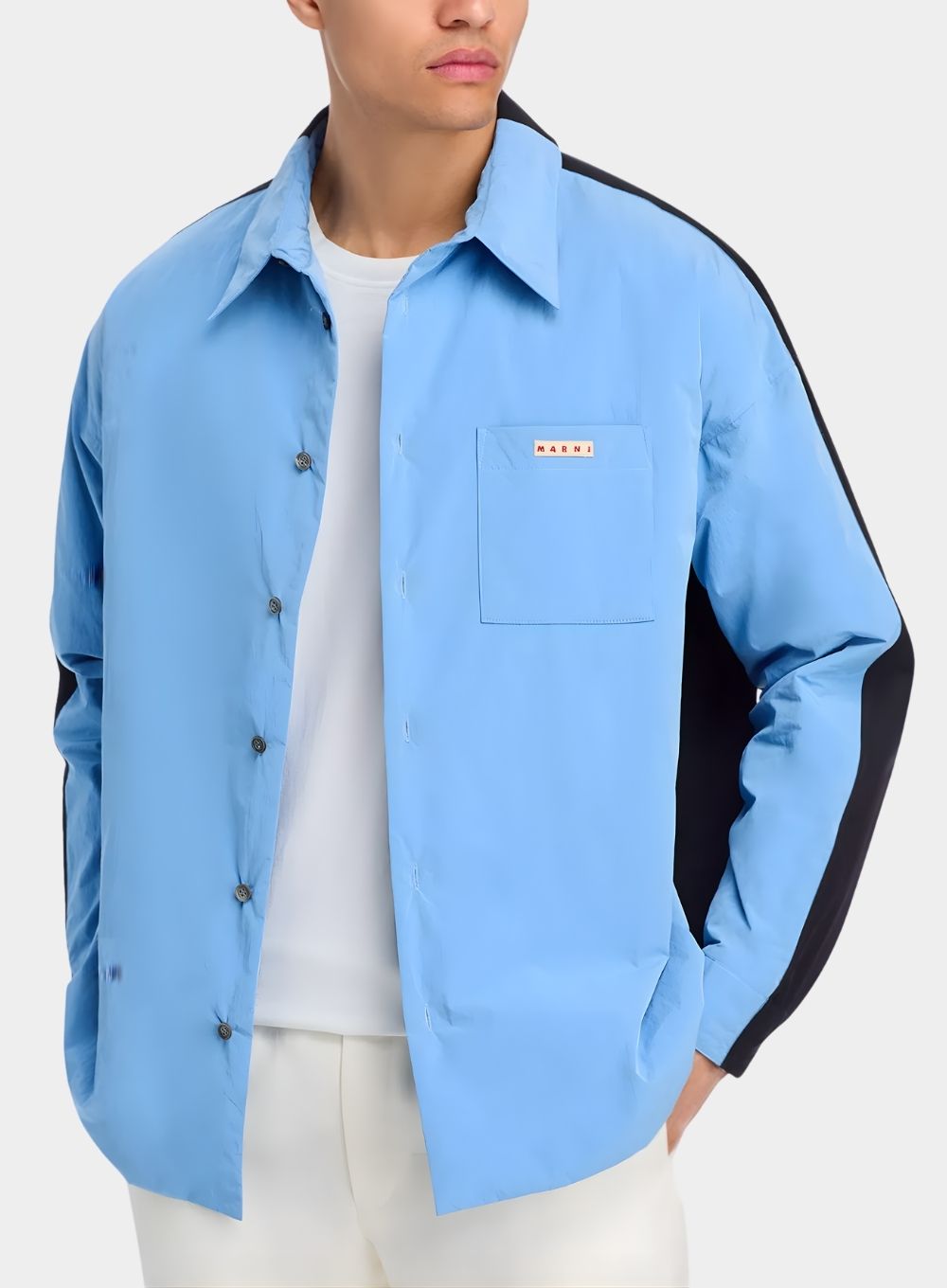 Light blue shirt with black sleeves worn by a person on a white background