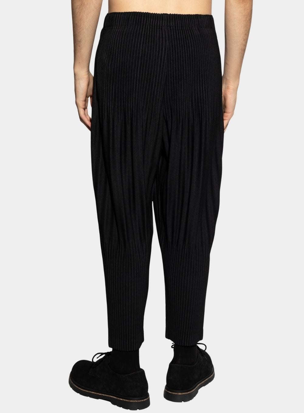 Person wearing black ribbed pants on a white background