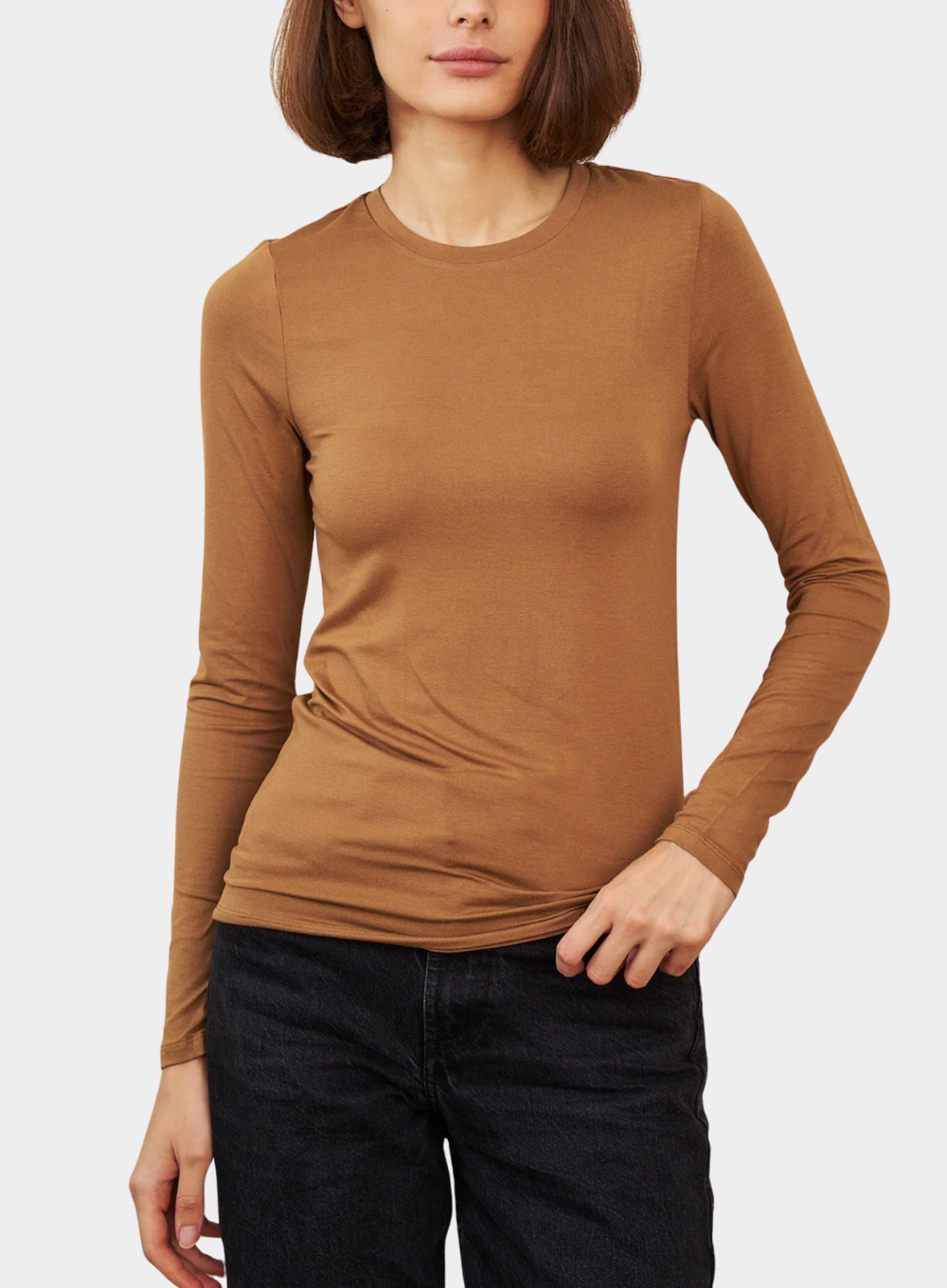 Woman wearing a brown long-sleeve top against a white background