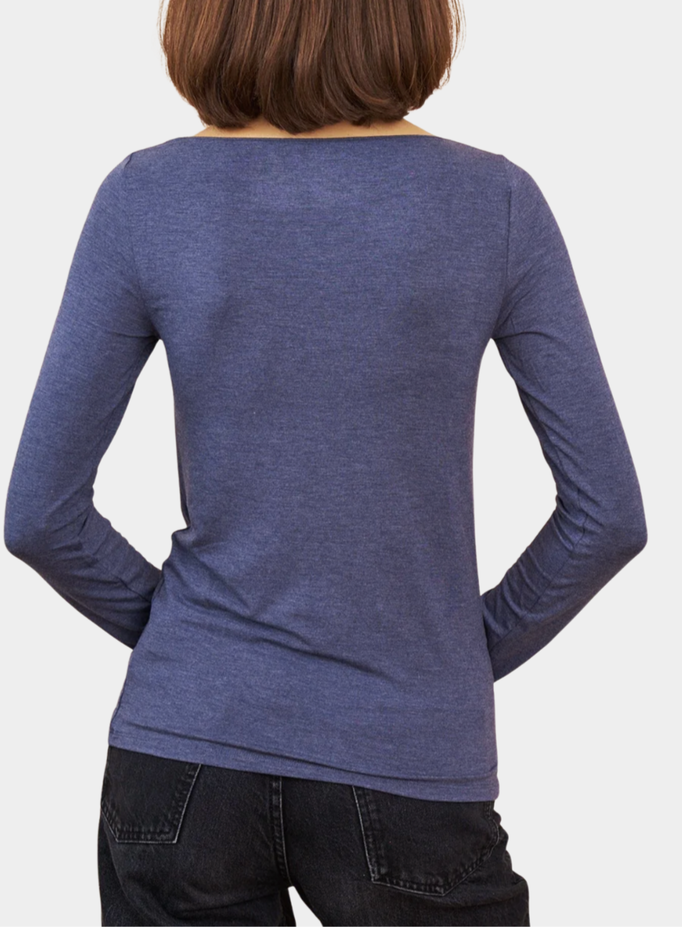 Person wearing a blue long-sleeve shirt with a plain background