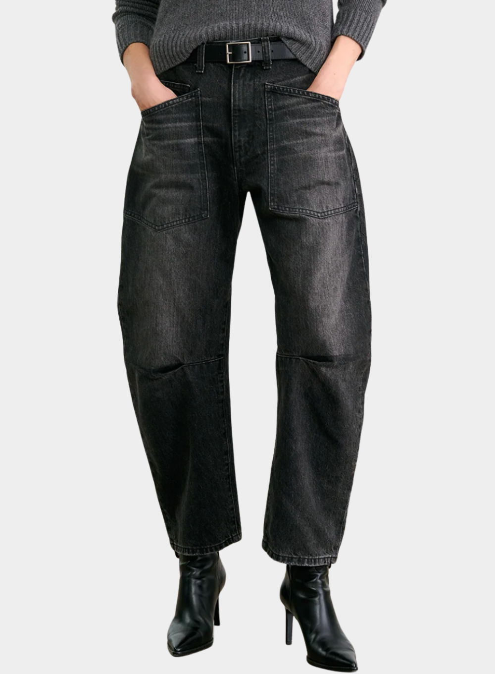 Person wearing black jeans and black boots on a light gray background